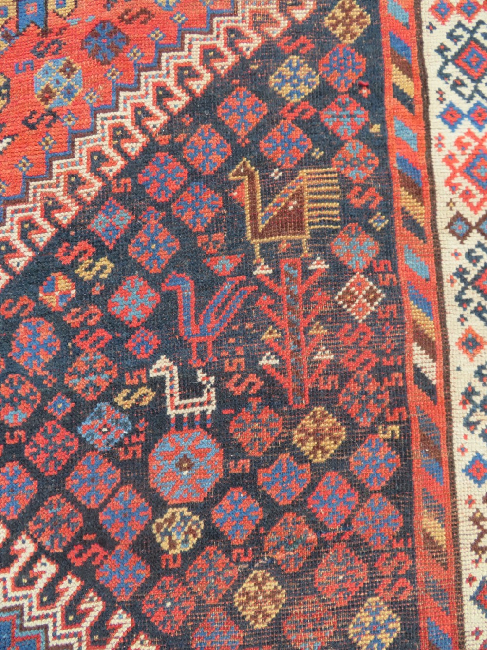 An antique Persian Luri hand-knotted wool carpet featuring three central diamond medallions surrounded by geometric tribal motifs and multi-banded borders. View VII