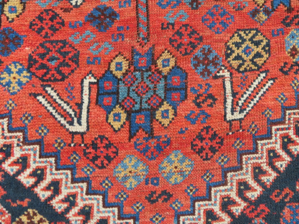 An antique Persian Luri hand-knotted wool carpet featuring three central diamond medallions surrounded by geometric tribal motifs and multi-banded borders. View VIII