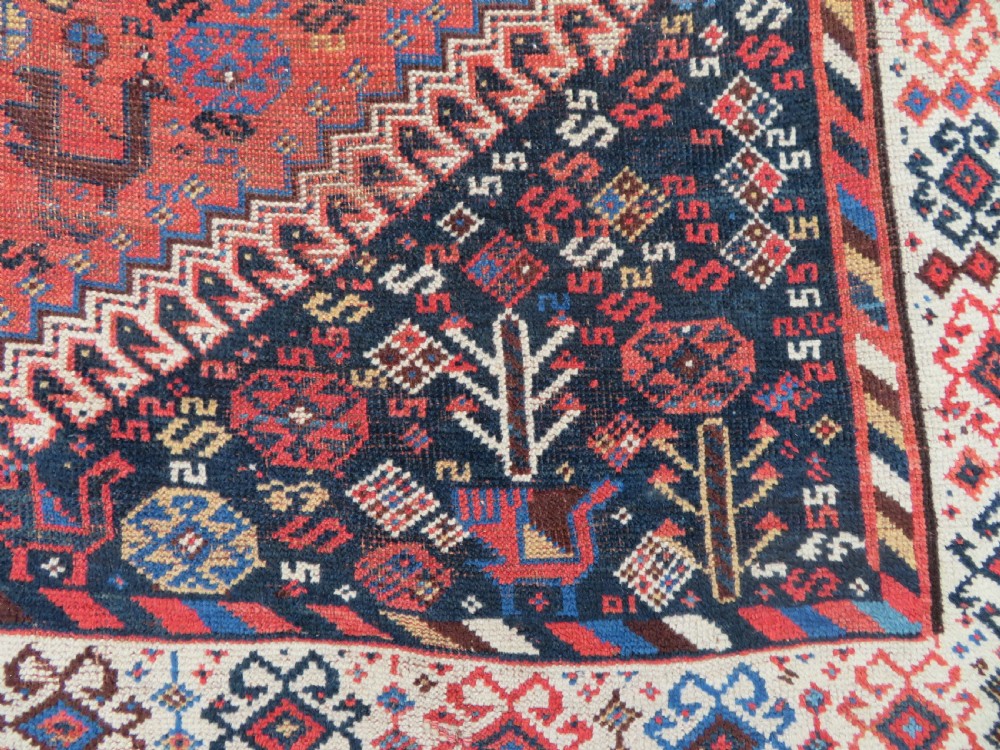 An antique Persian Luri hand-knotted wool carpet featuring three central diamond medallions surrounded by geometric tribal motifs and multi-banded borders. View X