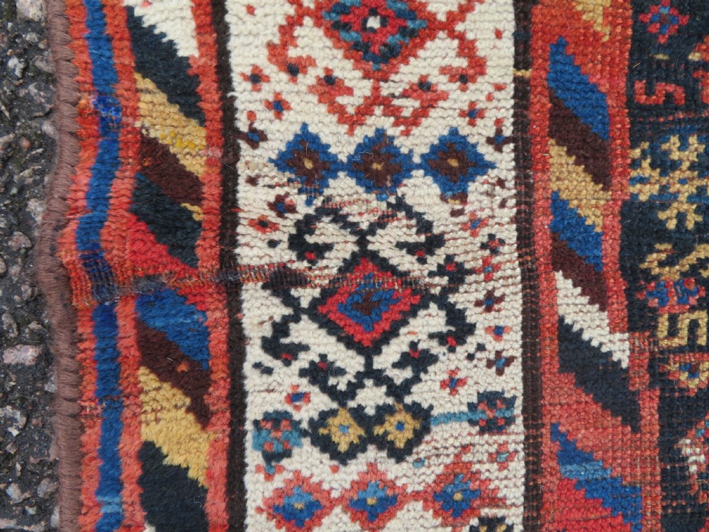 An antique Persian Luri hand-knotted wool carpet featuring three central diamond medallions surrounded by geometric tribal motifs and multi-banded borders. View XIII