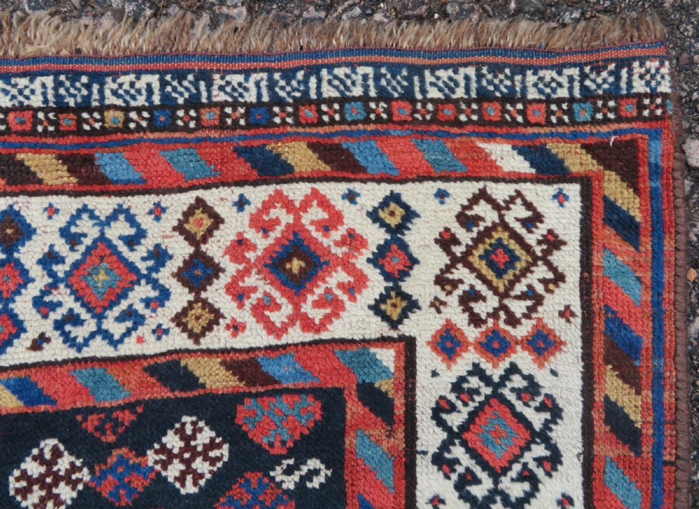 An antique Persian Luri hand-knotted wool carpet featuring three central diamond medallions surrounded by geometric tribal motifs and multi-banded borders. View XVIII