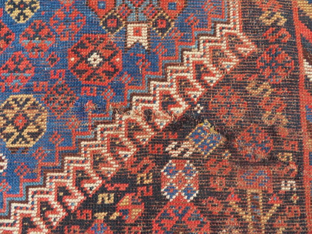 An antique Persian Luri hand-knotted wool carpet featuring three central diamond medallions surrounded by geometric tribal motifs and multi-banded borders. View XIX