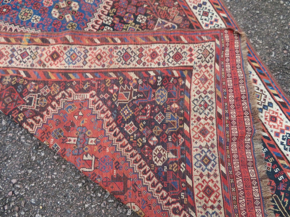 An antique Persian Luri hand-knotted wool carpet featuring three central diamond medallions surrounded by geometric tribal motifs and multi-banded borders. View XX
