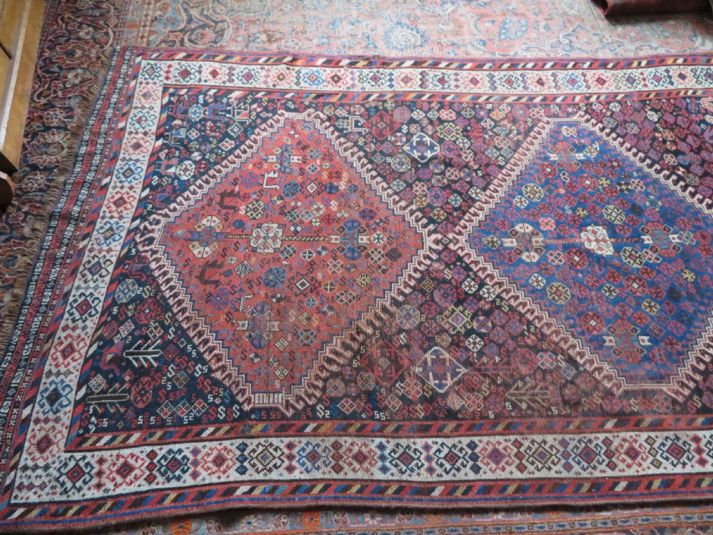 An antique Persian Luri hand-knotted wool carpet featuring three central diamond medallions surrounded by geometric tribal motifs and multi-banded borders. View XXIV