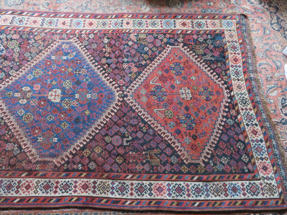 An antique Persian Luri hand-knotted wool carpet featuring three central diamond medallions surrounded by geometric tribal motifs and multi-banded borders. View XXV