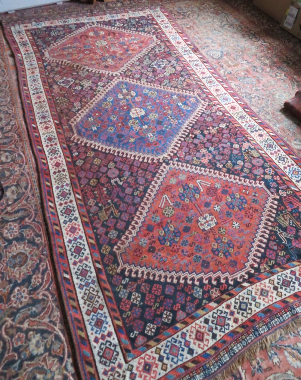 An antique Persian Luri hand-knotted wool carpet featuring three central diamond medallions surrounded by geometric tribal motifs and multi-banded borders. View XXVI