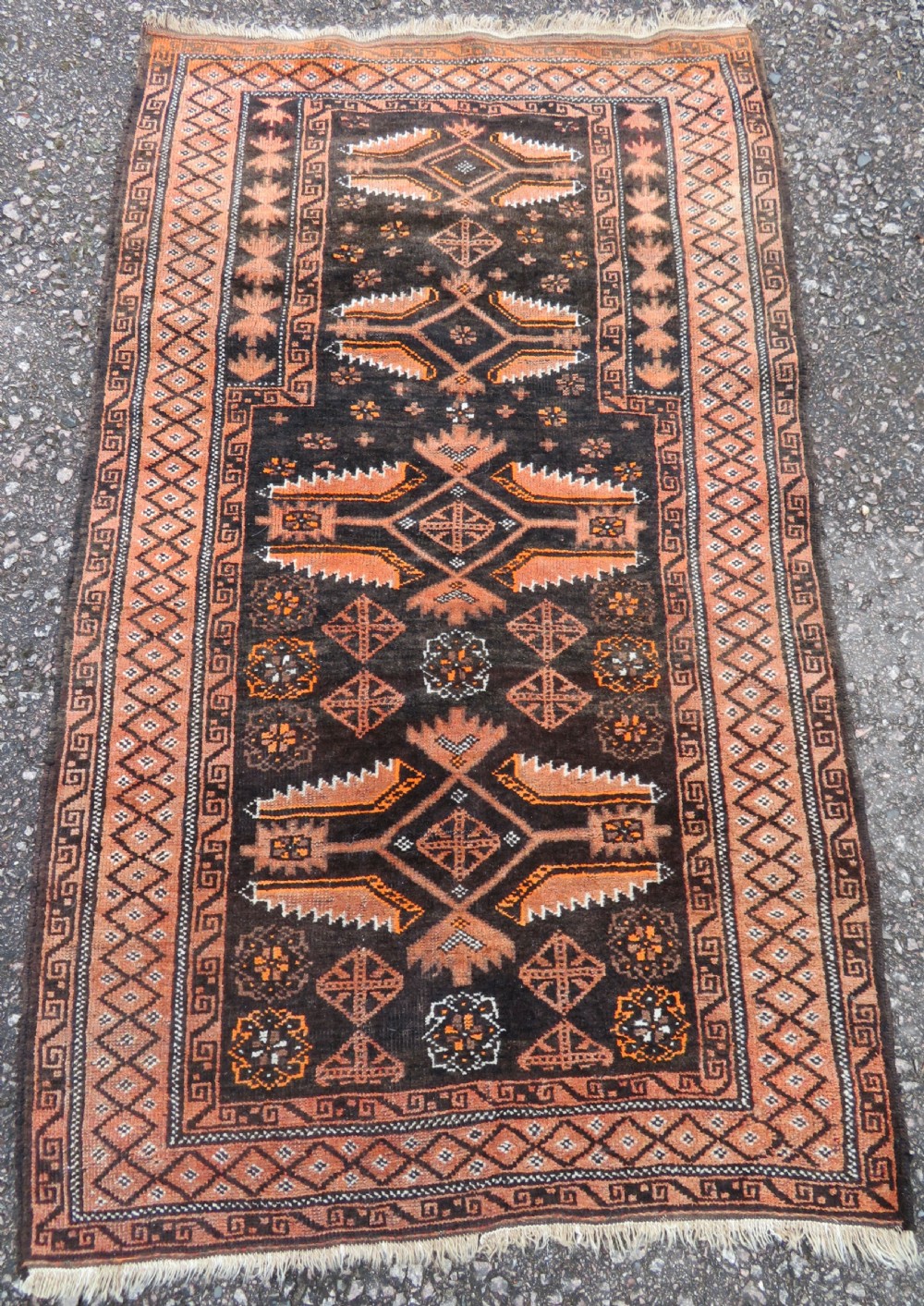 A hand-woven wool Afghan prayer rug featuring a dark brown central field with terracotta geometric motifs and a distinct pointed arch design.