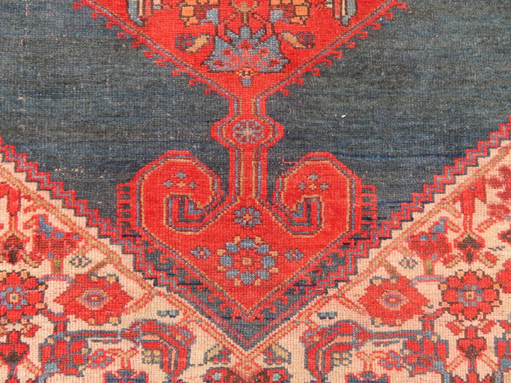 An antique hand-knotted Kurdish Bijar wool rug featuring a central red and blue medallion, cream patterned spandrels, and a terracotta floral border. View IV