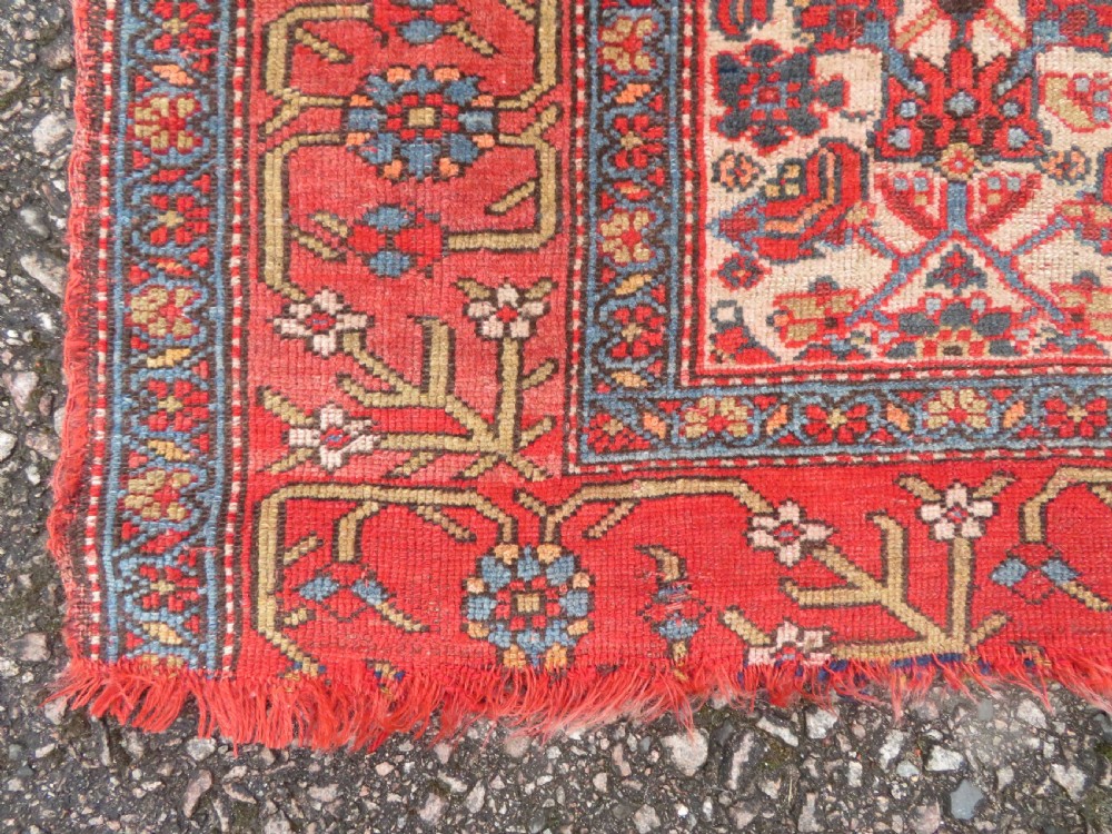 An antique hand-knotted Kurdish Bijar wool rug featuring a central red and blue medallion, cream patterned spandrels, and a terracotta floral border. View V