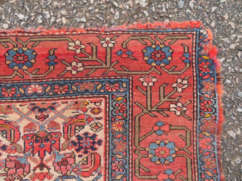 An antique hand-knotted Kurdish Bijar wool rug featuring a central red and blue medallion, cream patterned spandrels, and a terracotta floral border. View VII