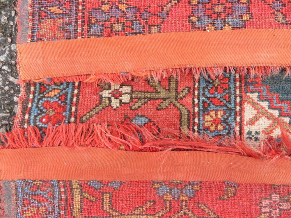 An antique hand-knotted Kurdish Bijar wool rug featuring a central red and blue medallion, cream patterned spandrels, and a terracotta floral border. View XII
