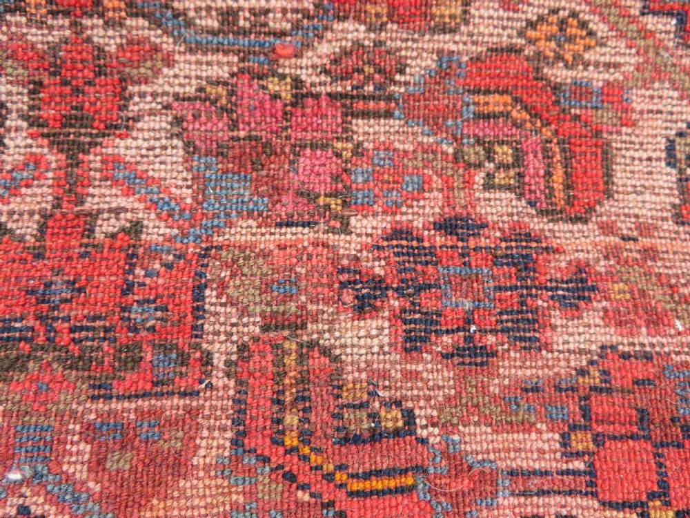 An antique hand-knotted Kurdish Bijar wool rug featuring a central red and blue medallion, cream patterned spandrels, and a terracotta floral border. View XIV