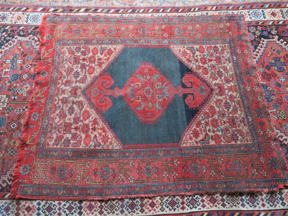 An antique hand-knotted Kurdish Bijar wool rug featuring a central red and blue medallion, cream patterned spandrels, and a terracotta floral border. View XVI
