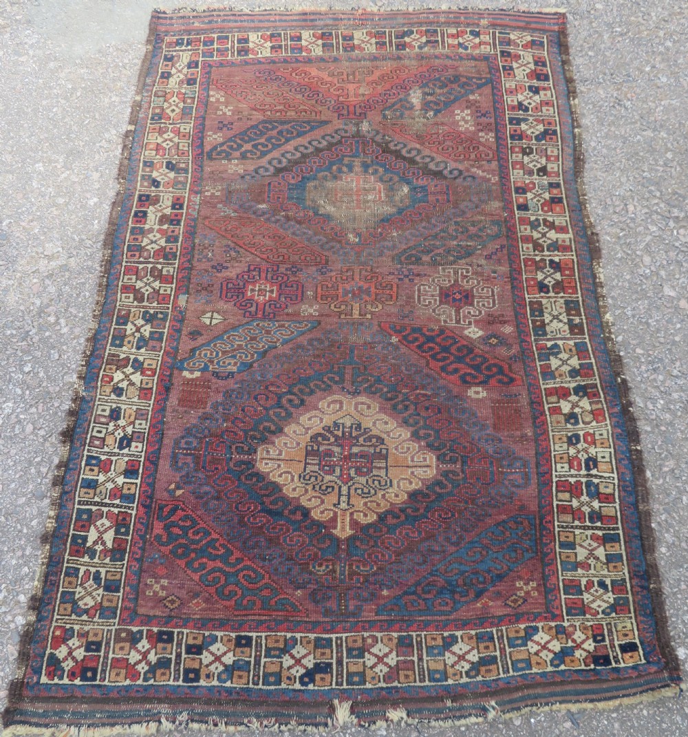 A rectangular distressed Persian Khamseh rug featuring repeating central diamond medallions in indigo blue and terracotta red surrounded by detailed geometric border bands.