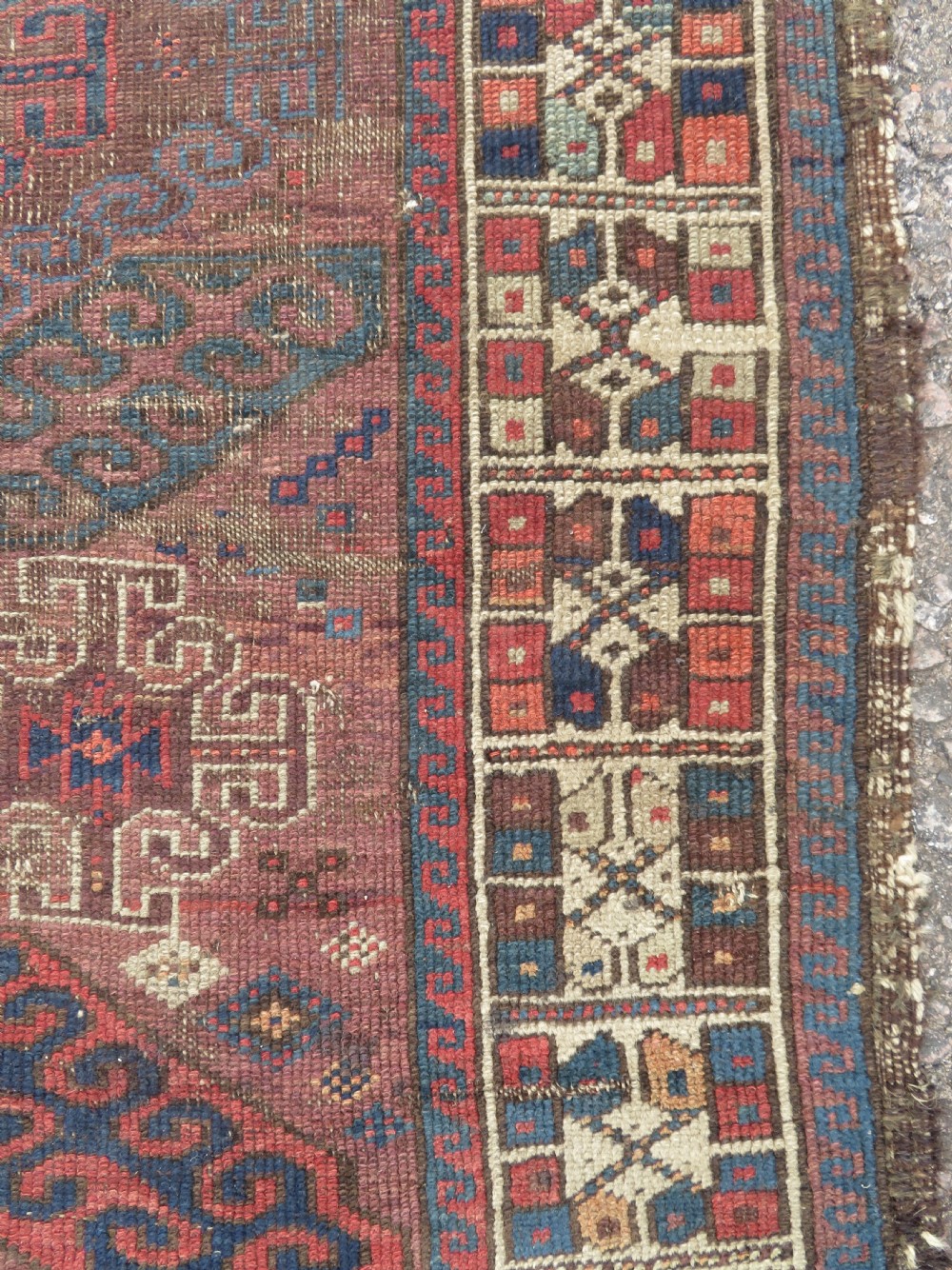 A rectangular distressed Persian Khamseh rug featuring repeating central diamond medallions in indigo blue and terracotta red surrounded by detailed geometric border bands. View V