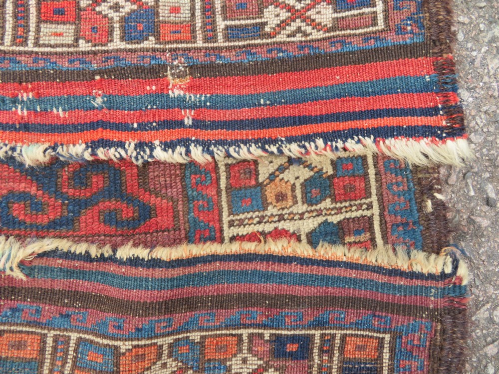A rectangular distressed Persian Khamseh rug featuring repeating central diamond medallions in indigo blue and terracotta red surrounded by detailed geometric border bands. View IX