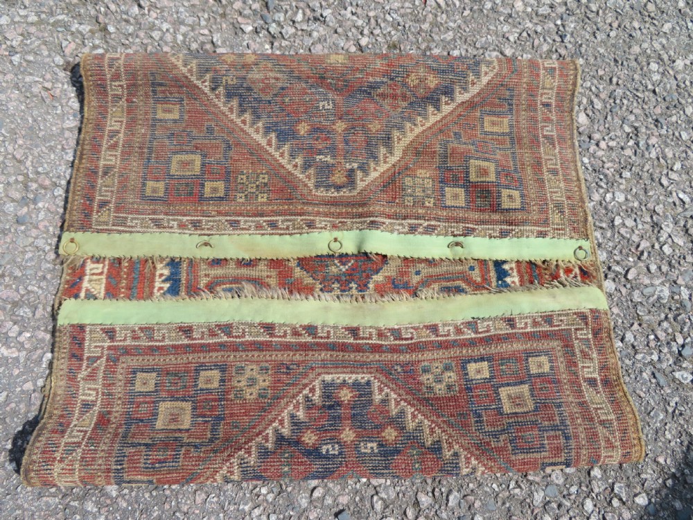 A small rectangular hand-knotted antique Khamseh rug featuring geometric tribal medallions in terracotta red, navy blue, and cream wool. View IX