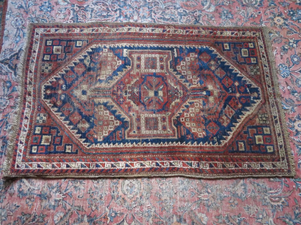 A small rectangular hand-knotted antique Khamseh rug featuring geometric tribal medallions in terracotta red, navy blue, and cream wool. View XIII