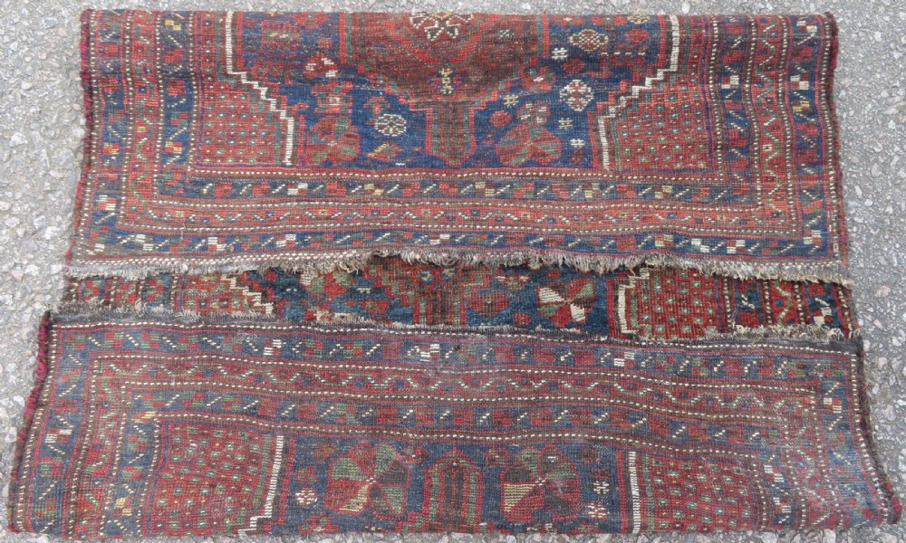 A distressed antique hand-knotted Khamseh tribal wool rug featuring three connected central medallions in red and indigo blue with geometric motifs. View X