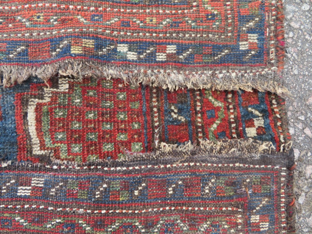 A distressed antique hand-knotted Khamseh tribal wool rug featuring three connected central medallions in red and indigo blue with geometric motifs. View XI
