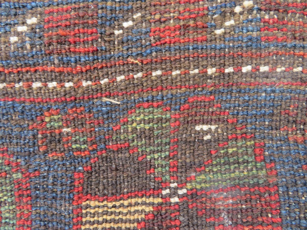 A distressed antique hand-knotted Khamseh tribal wool rug featuring three connected central medallions in red and indigo blue with geometric motifs. View XIII