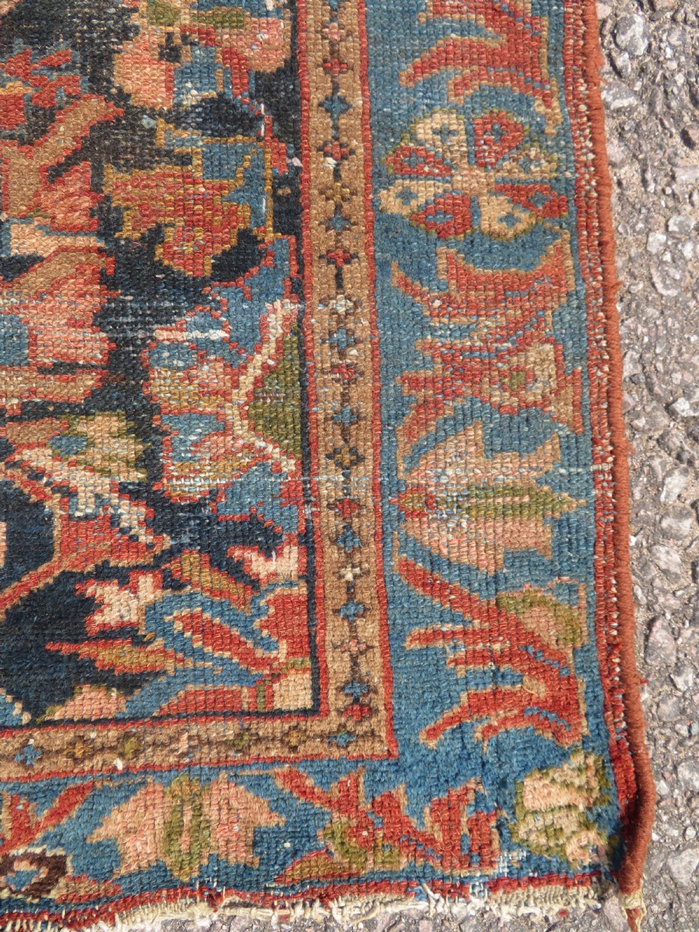 A small hand-knotted antique Sarouk wool rug featuring a dark blue field with central floral medallions and a terracotta and blue border. View V