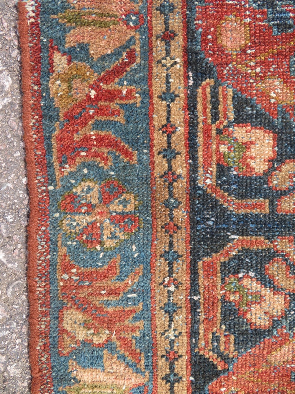A small hand-knotted antique Sarouk wool rug featuring a dark blue field with central floral medallions and a terracotta and blue border. View X
