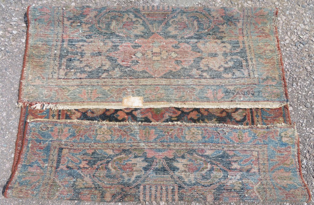 A small hand-knotted antique Sarouk wool rug featuring a dark blue field with central floral medallions and a terracotta and blue border. View XI