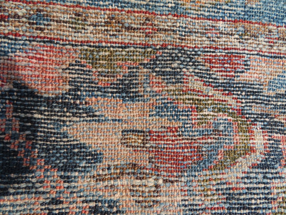 A small hand-knotted antique Sarouk wool rug featuring a dark blue field with central floral medallions and a terracotta and blue border. View XIII