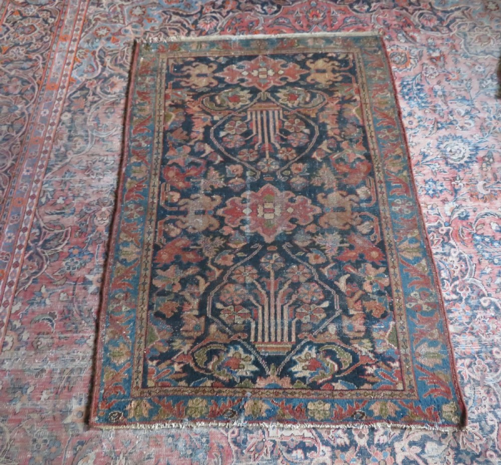 A small hand-knotted antique Sarouk wool rug featuring a dark blue field with central floral medallions and a terracotta and blue border. View XIV
