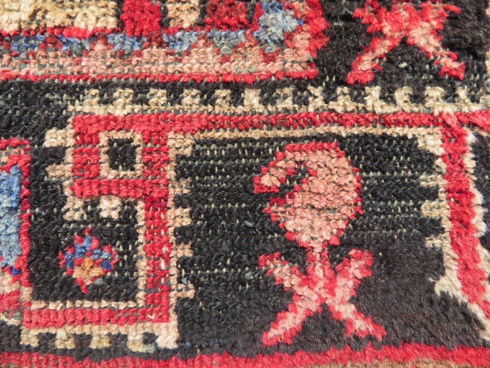 A rectangular distressed Persian Hamadan wool rug featuring a central stepped cross medallion on a crimson field with geometric borders. View VII
