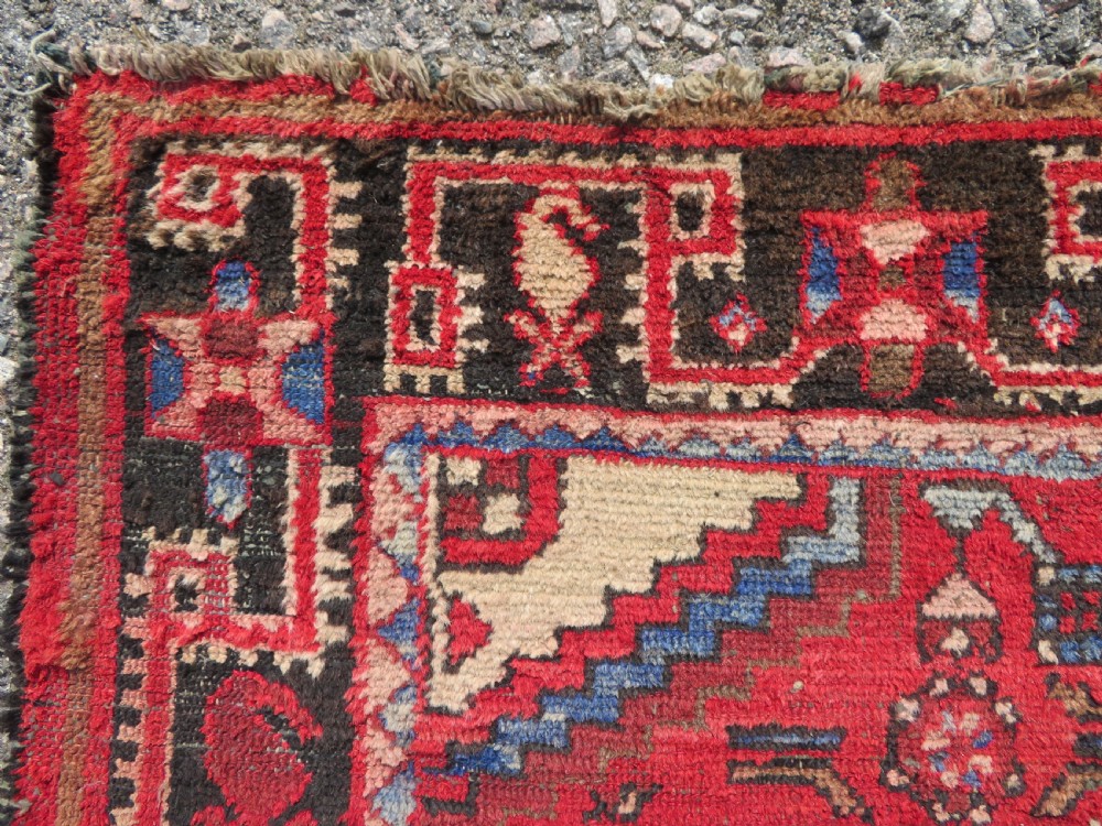 A rectangular distressed Persian Hamadan wool rug featuring a central stepped cross medallion on a crimson field with geometric borders. View IX