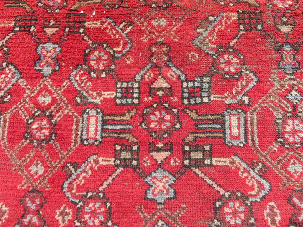 A rectangular distressed Persian Hamadan wool rug featuring a central stepped cross medallion on a crimson field with geometric borders. View XI