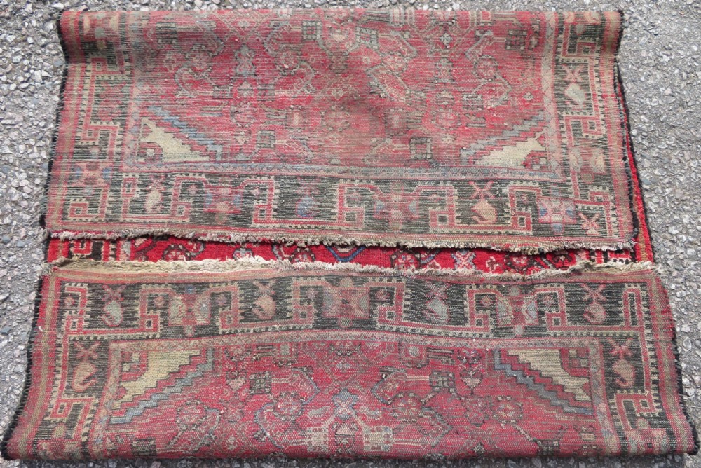 A rectangular distressed Persian Hamadan wool rug featuring a central stepped cross medallion on a crimson field with geometric borders. View XII