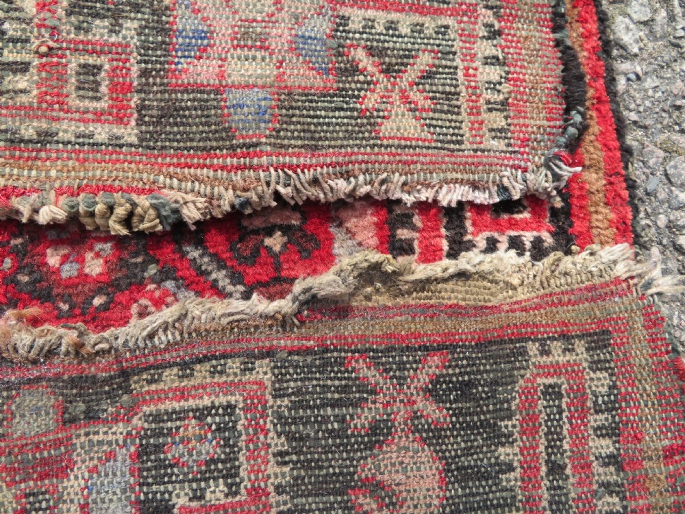 A rectangular distressed Persian Hamadan wool rug featuring a central stepped cross medallion on a crimson field with geometric borders. View XIV