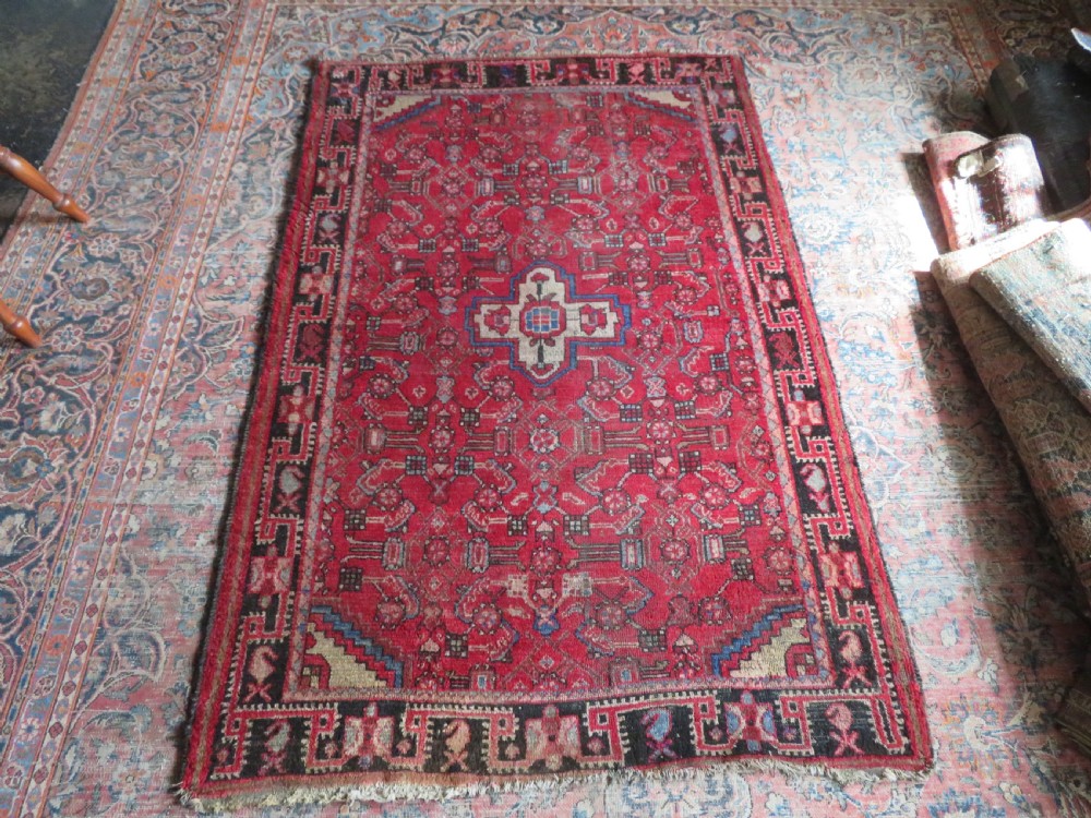 A rectangular distressed Persian Hamadan wool rug featuring a central stepped cross medallion on a crimson field with geometric borders. View XVI