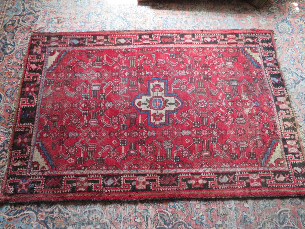 A rectangular distressed Persian Hamadan wool rug featuring a central stepped cross medallion on a crimson field with geometric borders. View XVII