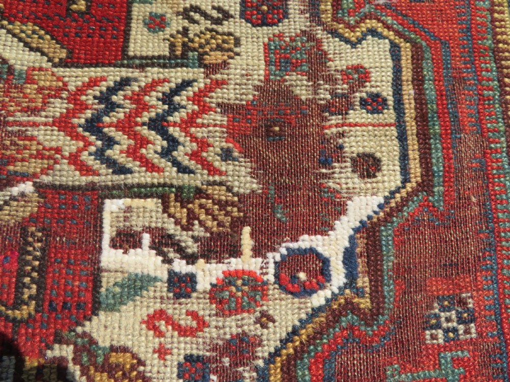 An antique hand-knotted Khamseh wool rug featuring a red central field with a geometric medallion framed by navy blue and cream borders. View IV