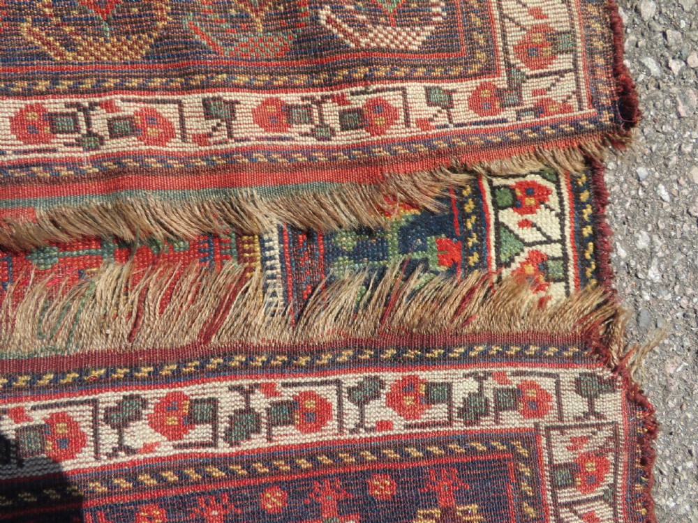 An antique hand-knotted Khamseh wool rug featuring a red central field with a geometric medallion framed by navy blue and cream borders. View XVII