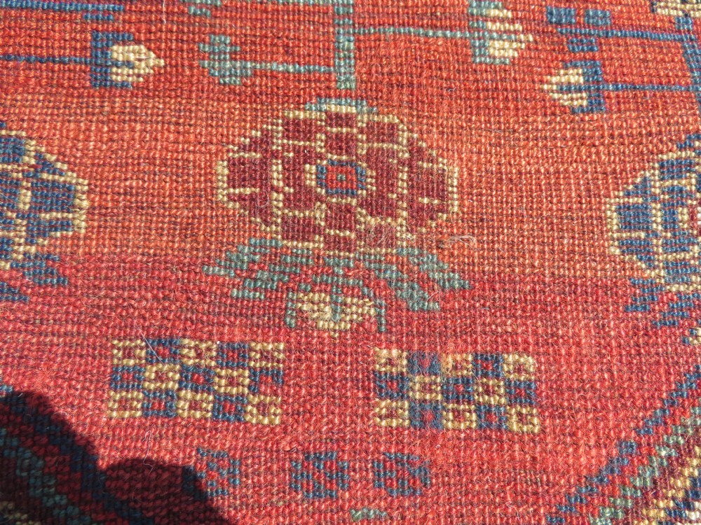 An antique hand-knotted Khamseh wool rug featuring a red central field with a geometric medallion framed by navy blue and cream borders. View XVIII