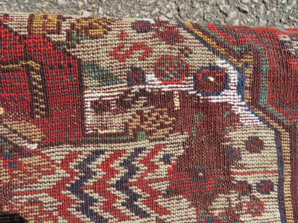 An antique hand-knotted Khamseh wool rug featuring a red central field with a geometric medallion framed by navy blue and cream borders. View XIX