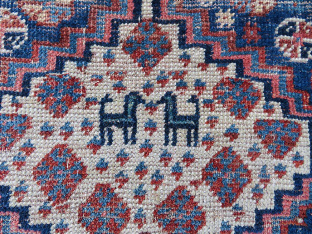 Distressed hand-knotted South Persian Khamseh tribal rug featuring nested diamond medallions, stylized animal motifs, and a multi-banded geometric border in navy blue, terracotta, and cream. View II