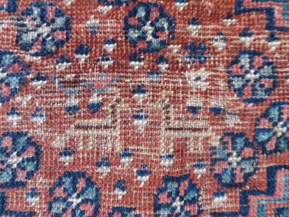 Distressed hand-knotted South Persian Khamseh tribal rug featuring nested diamond medallions, stylized animal motifs, and a multi-banded geometric border in navy blue, terracotta, and cream. View V