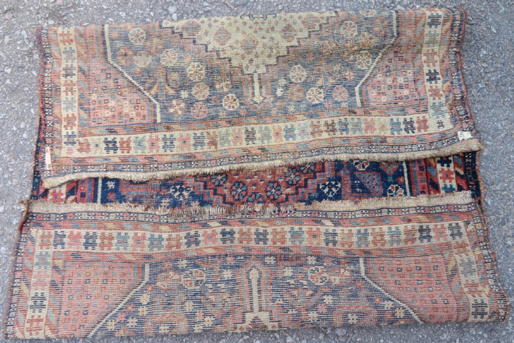 Distressed hand-knotted South Persian Khamseh tribal rug featuring nested diamond medallions, stylized animal motifs, and a multi-banded geometric border in navy blue, terracotta, and cream. View XIV