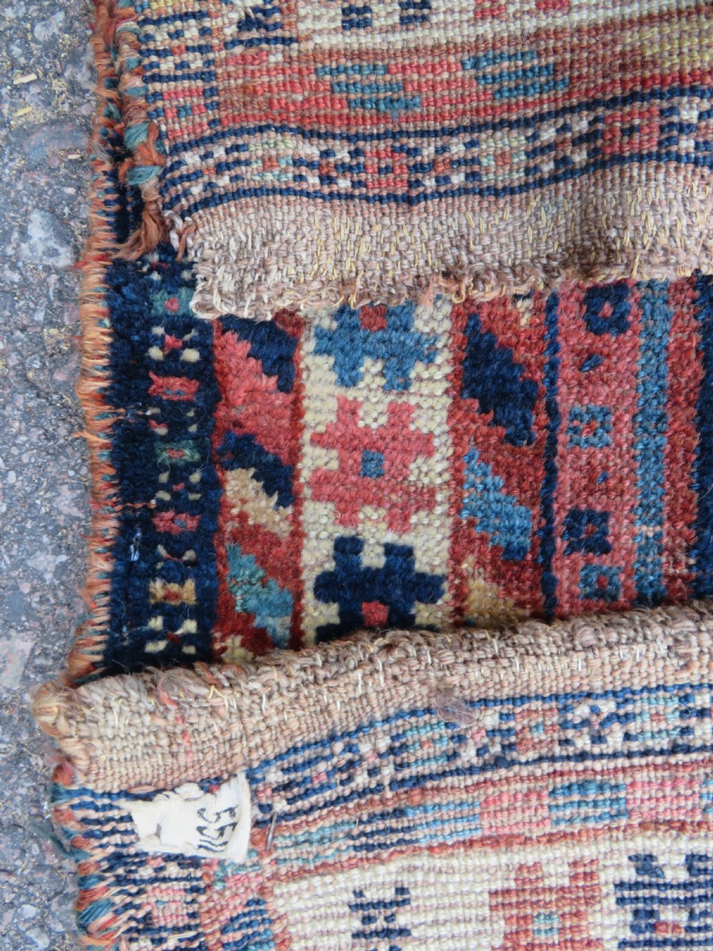 Distressed hand-knotted South Persian Khamseh tribal rug featuring nested diamond medallions, stylized animal motifs, and a multi-banded geometric border in navy blue, terracotta, and cream. View XV