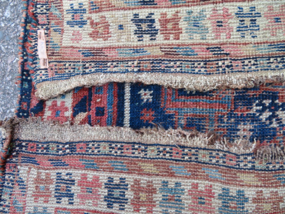 Distressed hand-knotted South Persian Khamseh tribal rug featuring nested diamond medallions, stylized animal motifs, and a multi-banded geometric border in navy blue, terracotta, and cream. View XVI