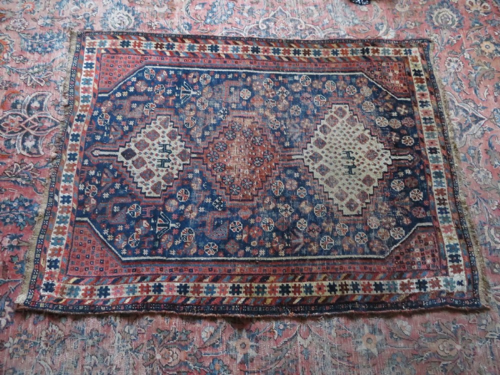 Distressed hand-knotted South Persian Khamseh tribal rug featuring nested diamond medallions, stylized animal motifs, and a multi-banded geometric border in navy blue, terracotta, and cream. View XIX