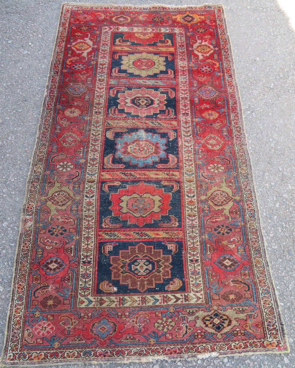 An antique hand-knotted North West Persian long rug featuring five geometric central medallions set against a dark field with a red pattern border.