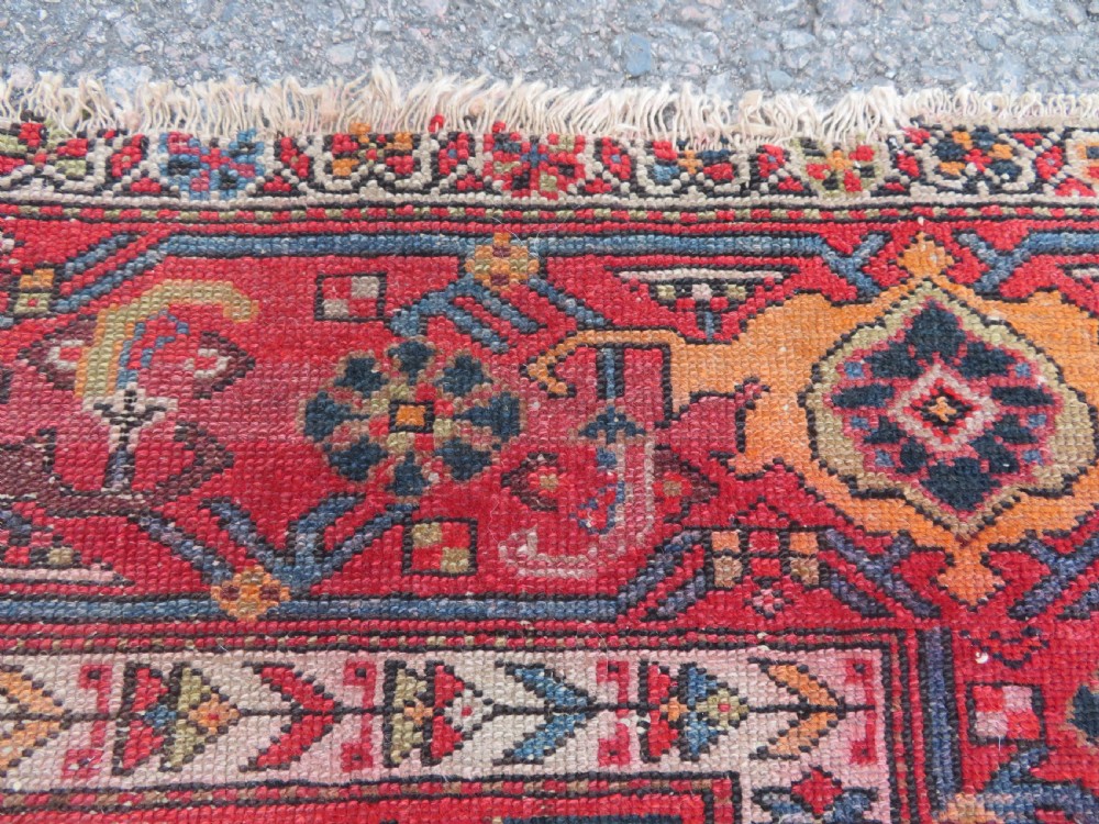 An antique hand-knotted North West Persian long rug featuring five geometric central medallions set against a dark field with a red pattern border. View VII