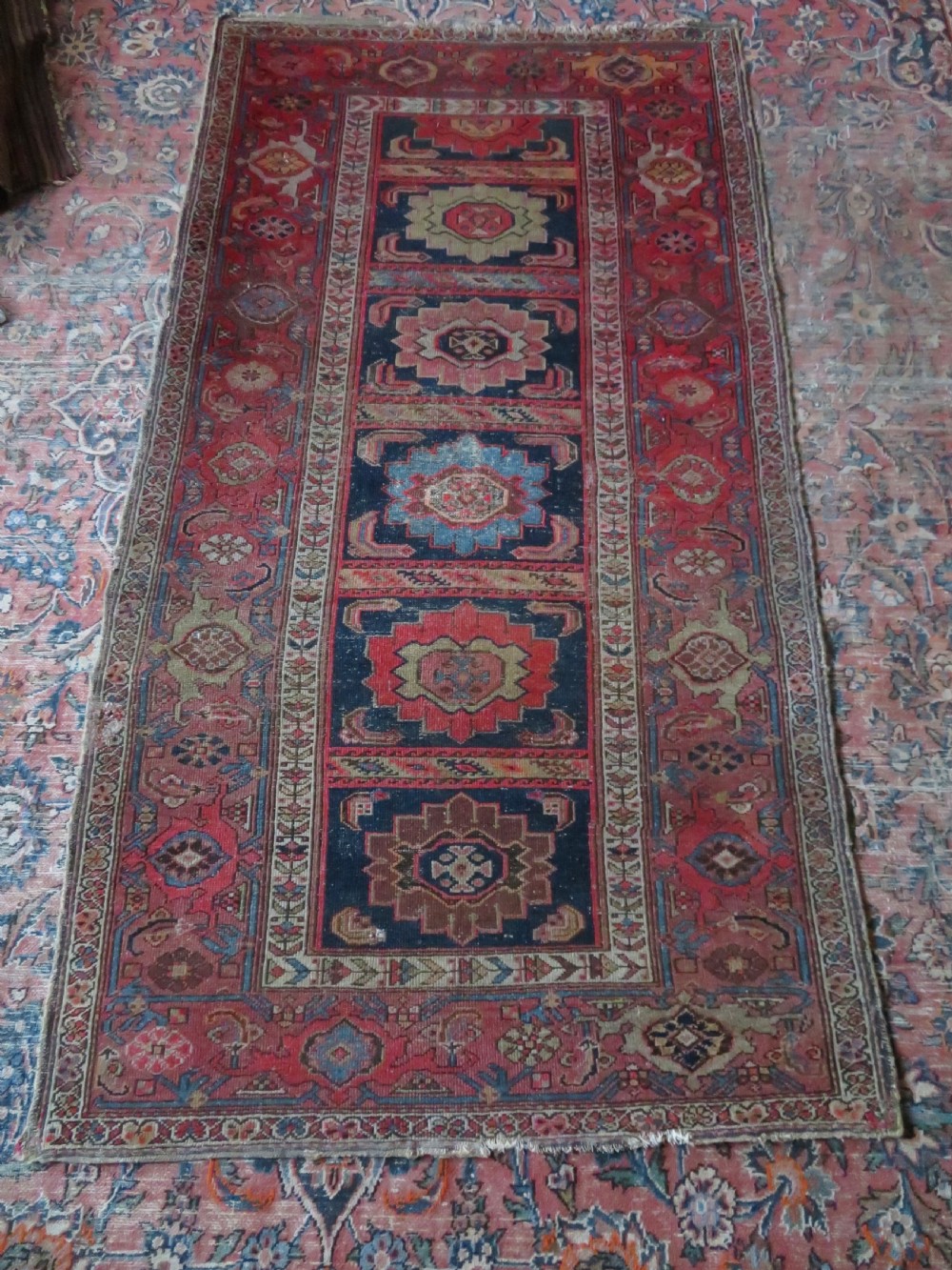 An antique hand-knotted North West Persian long rug featuring five geometric central medallions set against a dark field with a red pattern border. View XX
